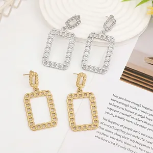 Detail of gold and silver chain-link rectangle earrings on a white embossed tray