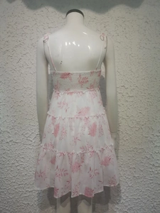 Detail view of the smocked back and tiered floral print skirt on this white summer dress