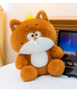 Plush brown cat toy sitting on a white desk next to a keyboard in a home office setting