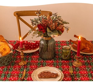 Detail of red and green plaid Christmas tablecloth with festive dining table setting