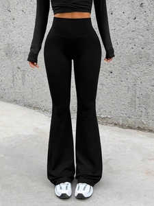 Detail view of black high-waisted flared yoga pants on model in an industrial studio