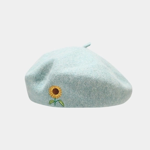 Detail of light blue wool beret featuring intricate yellow sunflower embroidery