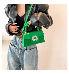 Detailed view of bright green leather crossbody bag featuring a sparkling crystal buckle
