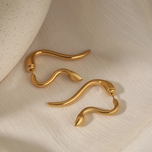 Polished 316 stainless steel snake shaped stud earrings in gold on beige fabric