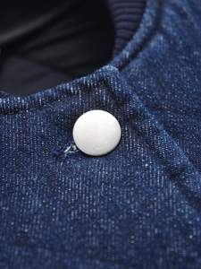Detailed macro view of silver metal button and texture on dark blue denim jacket