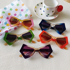 Fashionable oversized butterfly cat-eye sunglasses in multiple gradient colors set on a white table