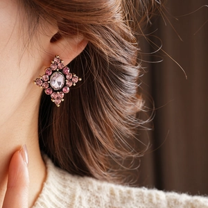 Dettaglio di orecchini vintage con gemme ovali rosa indossati da una modella