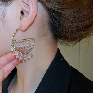 Close-up of golden geometric earrings with rectangular zircons on a female model