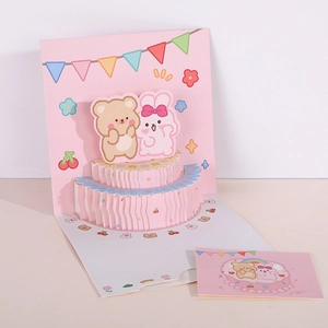 Macro shot of 3D pop-up birthday card with pink double-tier cake and cute cartoon animals
