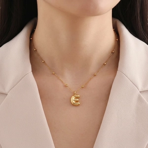 Detailed view of a gold-plated letter E pendant on a beaded satellite chain necklace