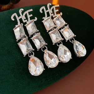 Detail of silver drop earrings with rectangle and pear-cut crystals on green velvet