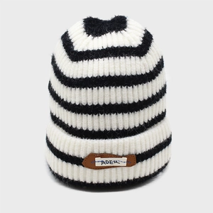 Macro detail of black and white striped knit beanie showing thick texture and ADER patch