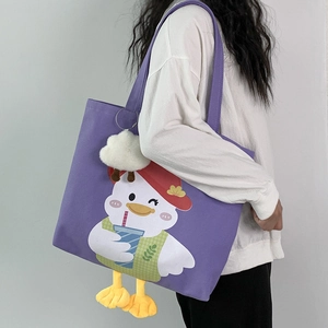 Detail of purple canvas tote bag featuring cartoon duck print and plush charms on a model
