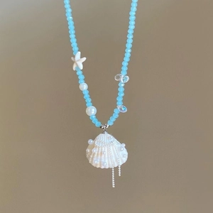 Close-up of blue beads necklace with white starfish, pearls and natural shell pendant