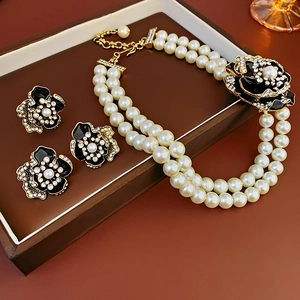 Flat lay of vintage floral jewelry set featuring black gold pearls and crystal accents
