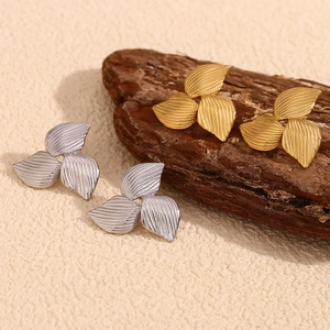 Macro detail of boomerang stud earrings in gold and silver finish with striped texture