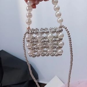 Detail of silver beads and cream pearls woven on a mini crossbody bag with metal chain