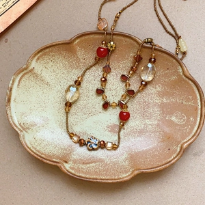 Detail of vintage beaded necklace with ceramic floral beads and amber crystals on a tray