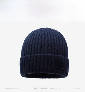 Detail of navy blue ribbed knit beanie featuring a black fashion label with white R letter