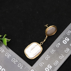 Baroque pearl earrings with 925 silver needles and gold wire wrap on black background