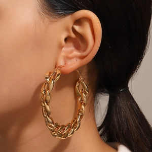 Gros plan de boucles d'oreilles créoles dorées à gros maillons portées par un mannequin