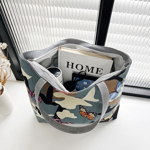 Green canvas tote bag with butterfly prints showing spacious interior for books and gadgets