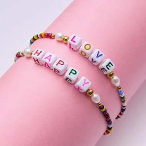 Detail of beaded bracelet set with LOVE and HAPPY letter beads on pink display stand