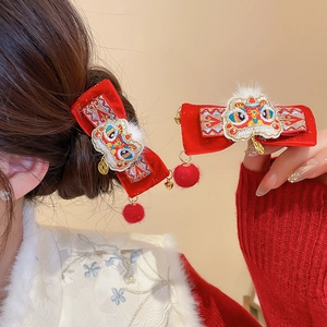 Detail of red velvet bow hair clips with traditional lion dance embroidery and gold coins