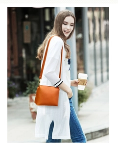 Detail of bright orange lychee textured leather crossbody bag with golden hardware