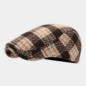 Detailed close-up of brown and beige plaid wool tweed texture on classic flat cap