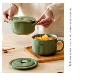 Close-up of olive green ceramic noodle bowl with vertical stripes and handle