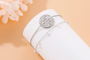Detail of a silver double-layer stainless steel bracelet with compass pendant and pearls