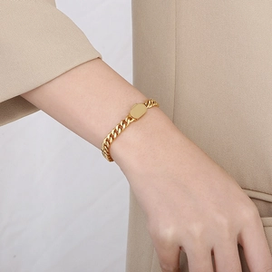 Gros plan d'un bracelet gourmette doré avec plaque rectangulaire porté au poignet
