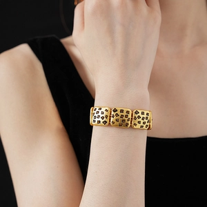 Close-up of golden leopard print bracelet with orange gemstones on model wrist