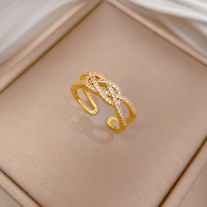Close-up of gold-plated twisted cross ring featuring shimmering pavé cubic zirconia details