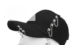 Detail view of black punk baseball cap featuring silver metal rings and hanging chains