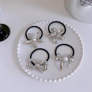 Detailed set of silver flower and bow hair ties with pearls on a ceramic tray
