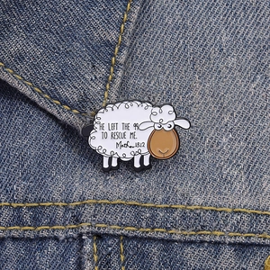 Detail of cute sheep enamel pin on denim with HE LEFT THE 99 TO RESCUE ME text engraving