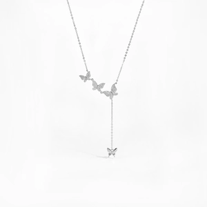 Macro detail of the Y-shaped silver necklace with pavé diamond butterfly pendants