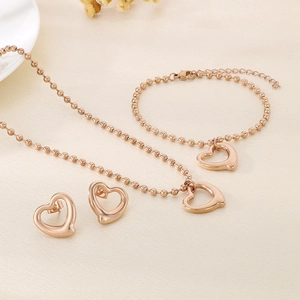 Vue détaillée de la parure en or rose avec pendentifs cœur ajourés et chaîne à billes