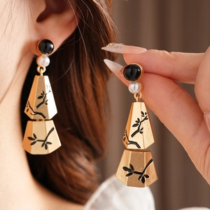 Close-up of vintage gold tassel earrings with black and white pearls and branch patterns