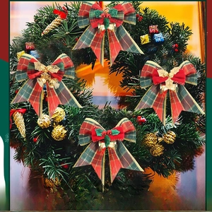 Close-up of Christmas plaid bows with gold bells and red berries on a festive pine wreath