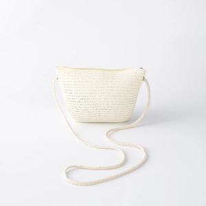 Détail d'un sac bandoulière en paille tressée beige avec fermeture et longue corde
