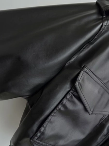 Detailed close-up of the fine stitching and side flap pocket on a black faux leather jacket