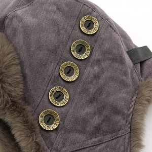 Macro detail of charcoal winter trapper hat with vintage brass buttons and faux fur trim