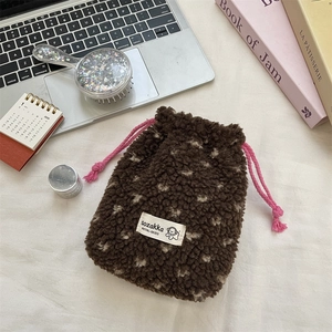 Close-up of brown plush drawstring pouch with pink cords on a tidy desktop