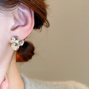 Close-up of flower pearl stud earring worn on ear with polished silver finish