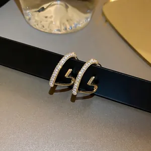 Elegant gold plated heart earrings with zircon stones on a black display stand