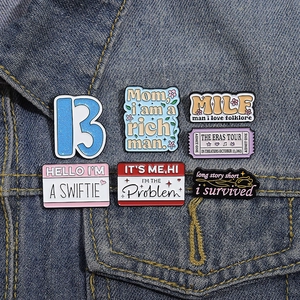 Detail of colorful enamel Swiftie pins and Eras Tour badges on a blue denim jacket