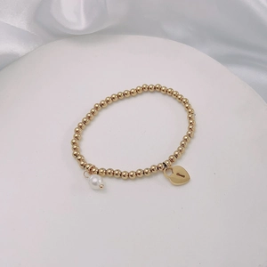 Detail of 18k gold beaded bracelet with heart padlock and white pearl pendant charms